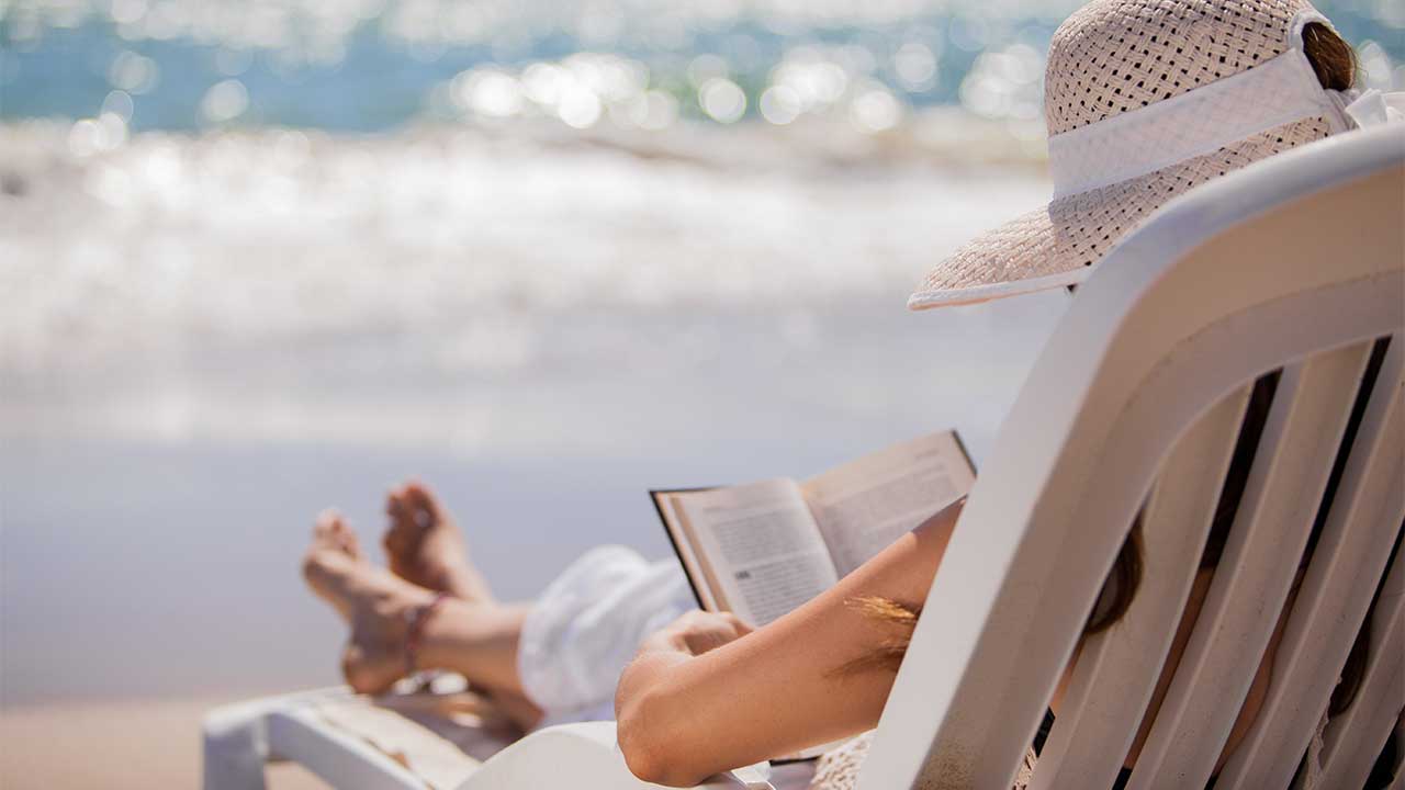 Woman reading a book while on a beach